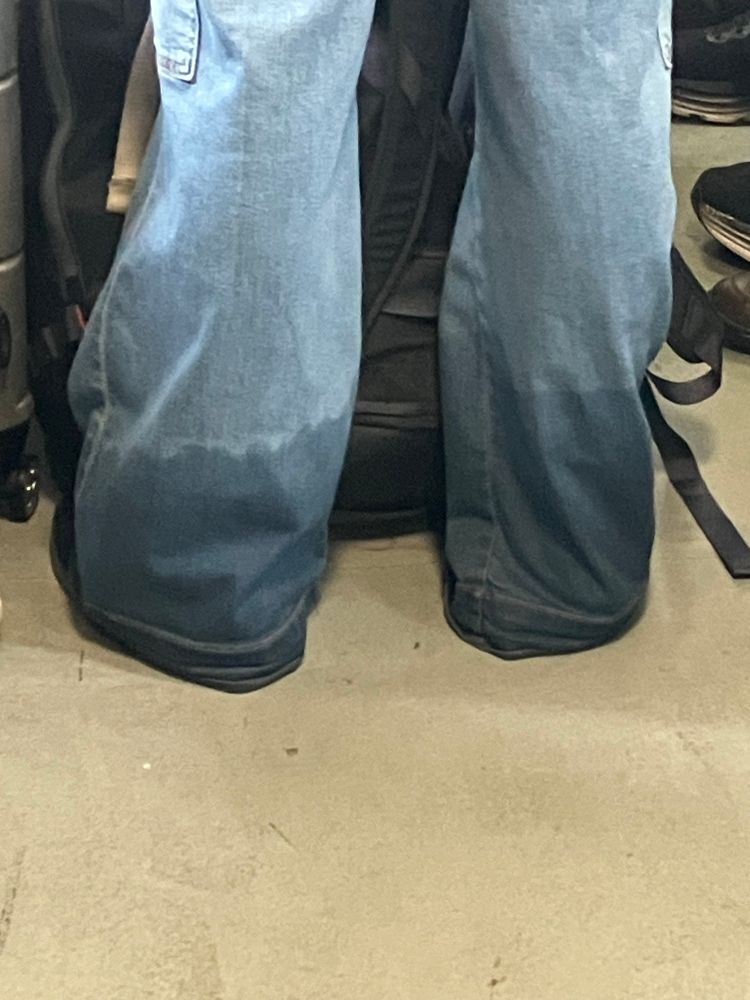 A picture of a girl wearing a pair of long, oversized jeans. The bottom 10-12 inches of the jeans from hem up are soaking wet 
