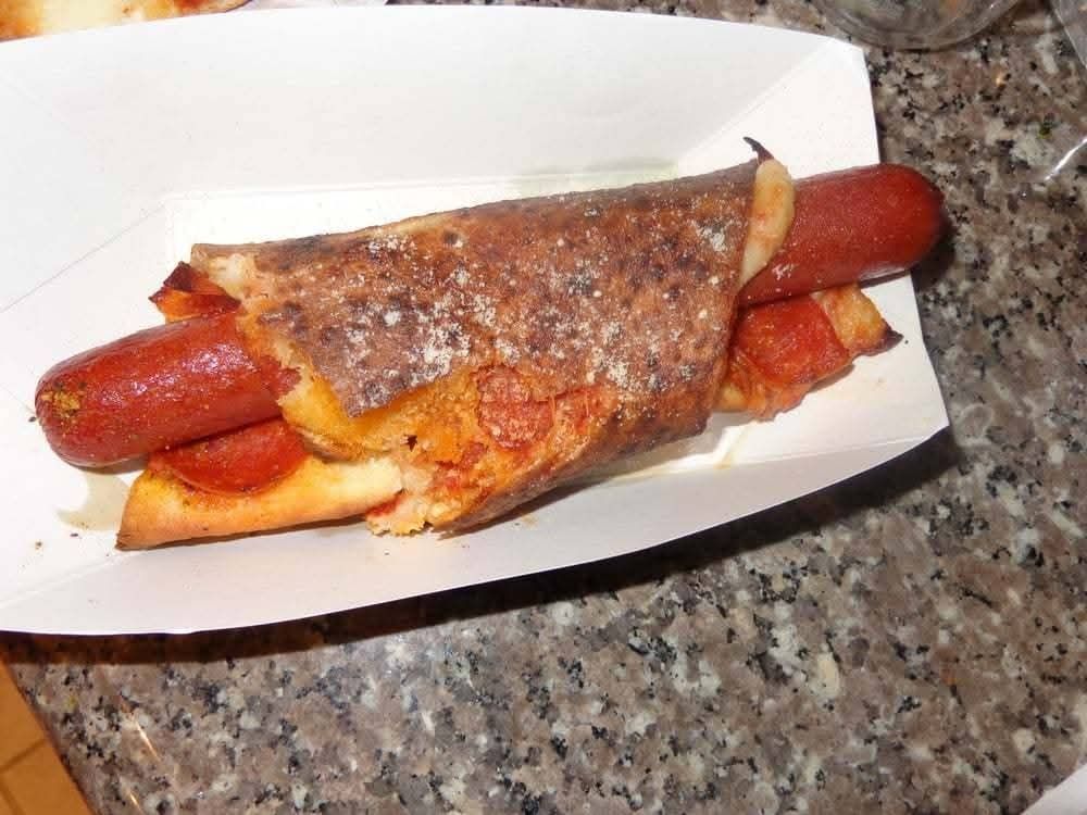 A hot dog wrapped in a slice of pepperoni pizza