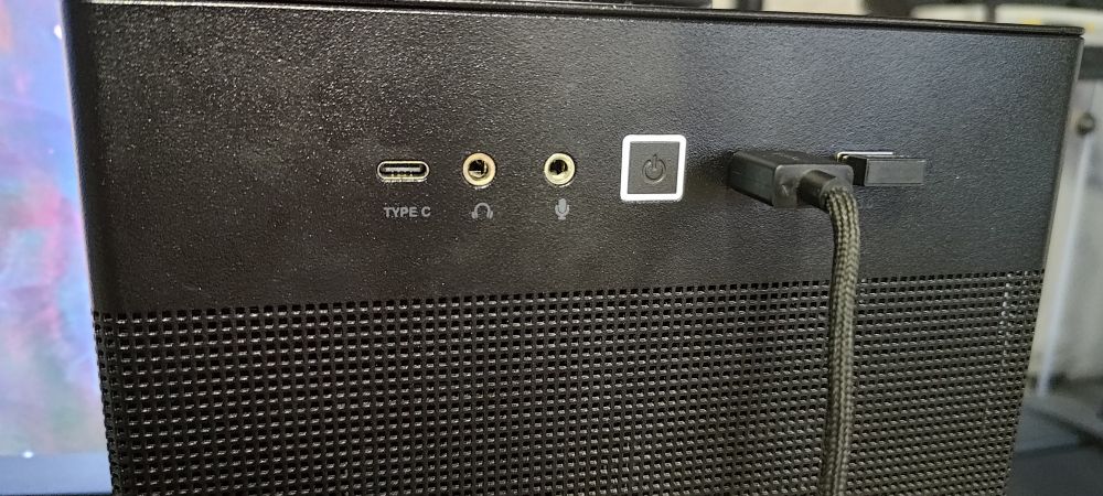 A photo of the front panel of an ASUS AP201 case, showing off the replaced headphone jack. The only noticeable sign is a slightly darker tone on the metal ring compared to the microphone jack beside it 