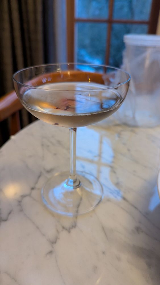 clear cocktail with red bleeding hibiscus petal