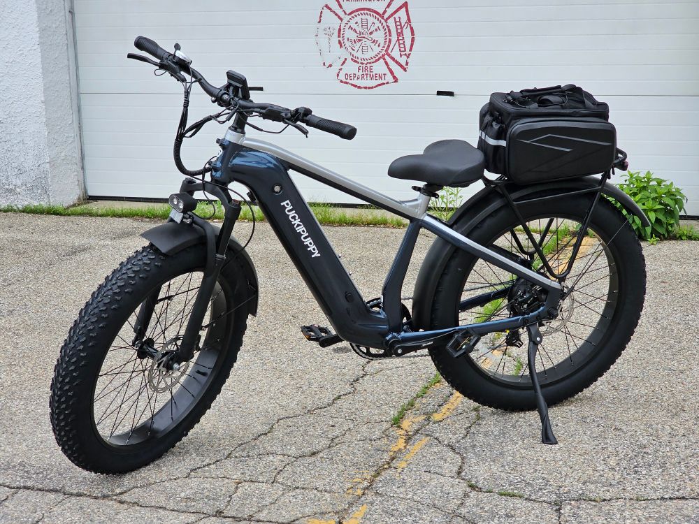 A blue and gray e-bike parked in front of a white building