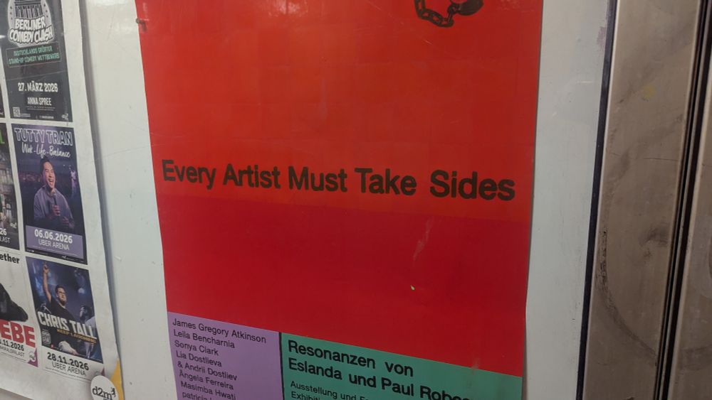 Plakat in der U-Bahn, schwarze Schrift auf rotem Grund: "Every Artist Must Take Sides"