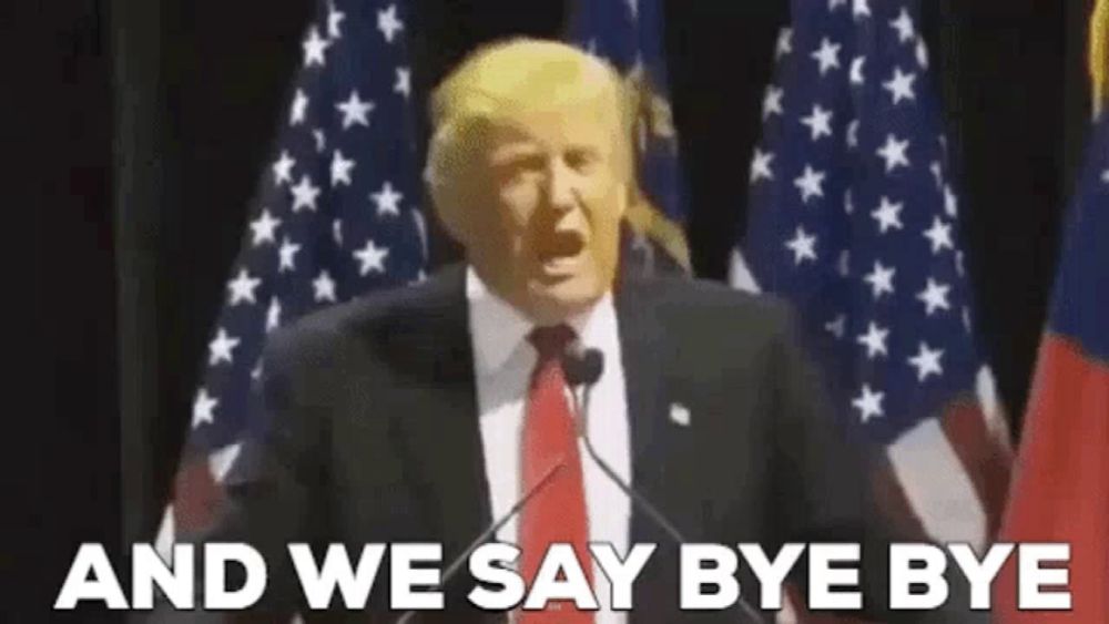 a man in a suit and tie is giving a speech in front of an american flag .