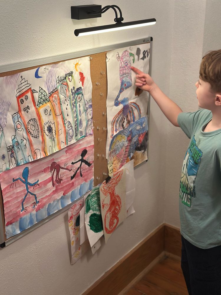 Child pointing at artwork on bulletin board