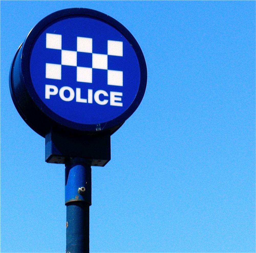Police sign against background of blue sky.