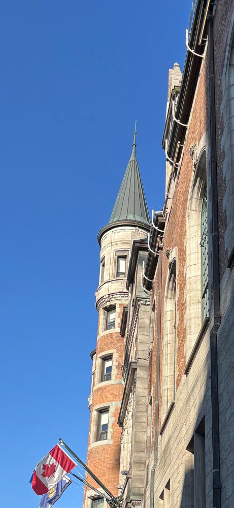 Some windows on a hotel round corner structure with Canadian flag on bottom of photo 