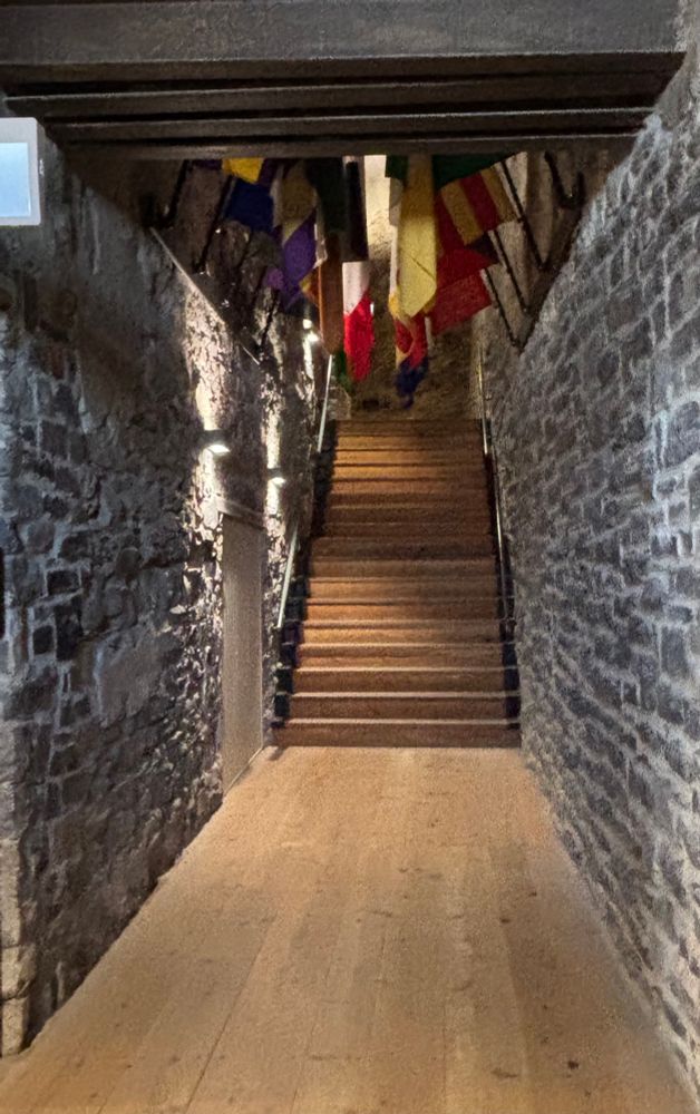 A wooden staircase with stone walls with flags at the top