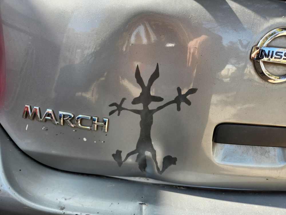 Puerta de auto abollada con adhesivo de la silueta del Coyote del Correcaminos.