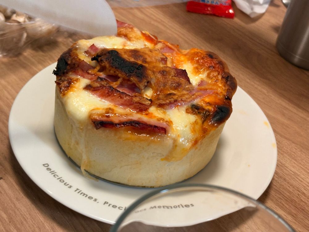 生地から作ってもらったシカゴピザ(耳が壁みたいになってるピザ)を写した写真です。
トッピングとしてベーコンやチーズが山々と盛られています。