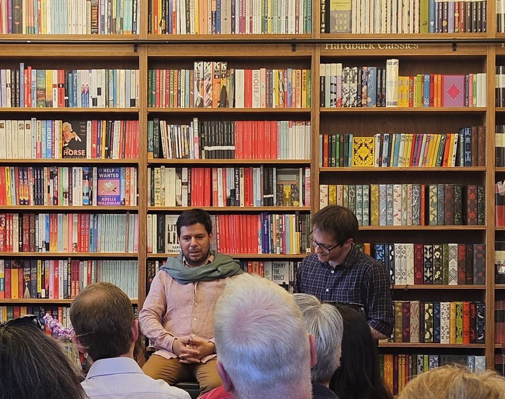Renato and Dylan talking in front of huge book shelf