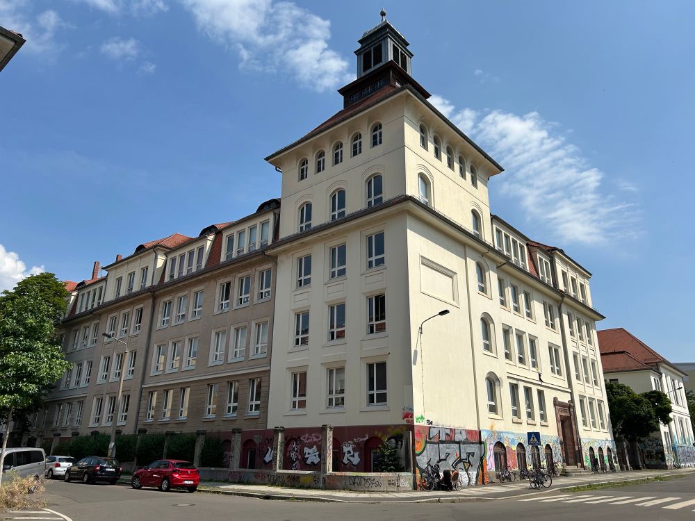 Man sieht ein winklig gebautes Gebäude mit einem auffallend großen Eckturm.