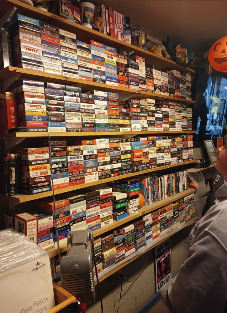 A big stack of movies on VHS, with some movie memorabilia on the sides.