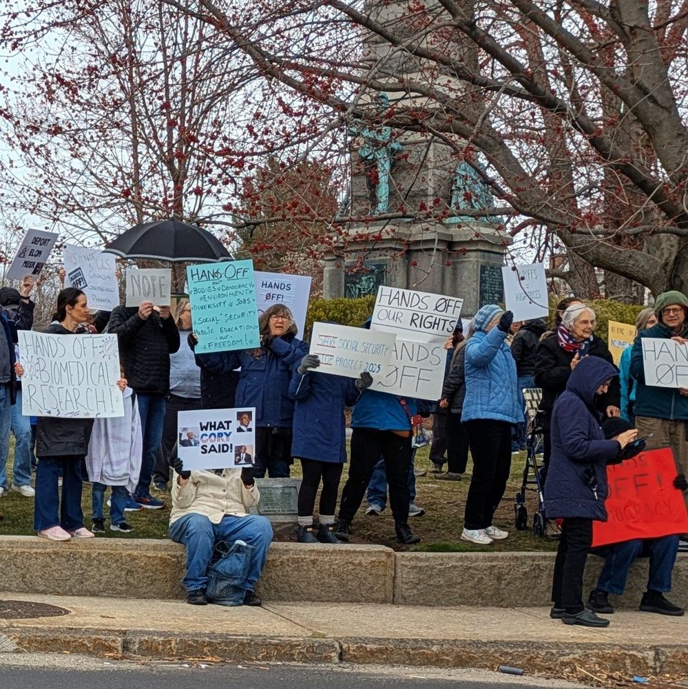Protesters holding signs with messaging "what Cody said" and "Hands off"
