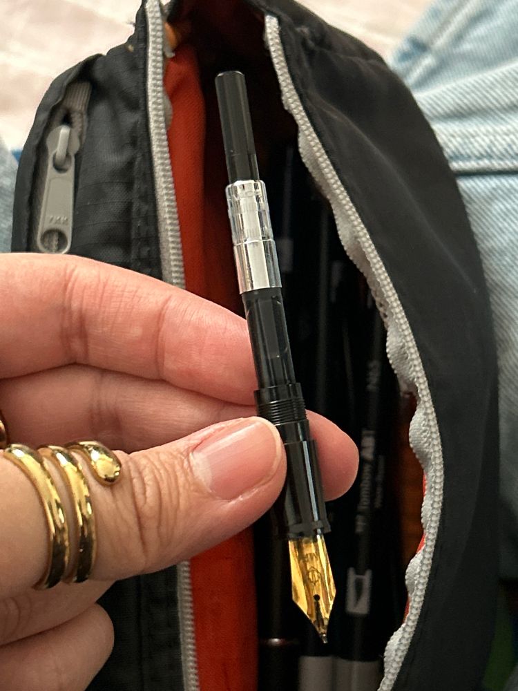 fountain pen ink converter with a black and orange pencil case behind it