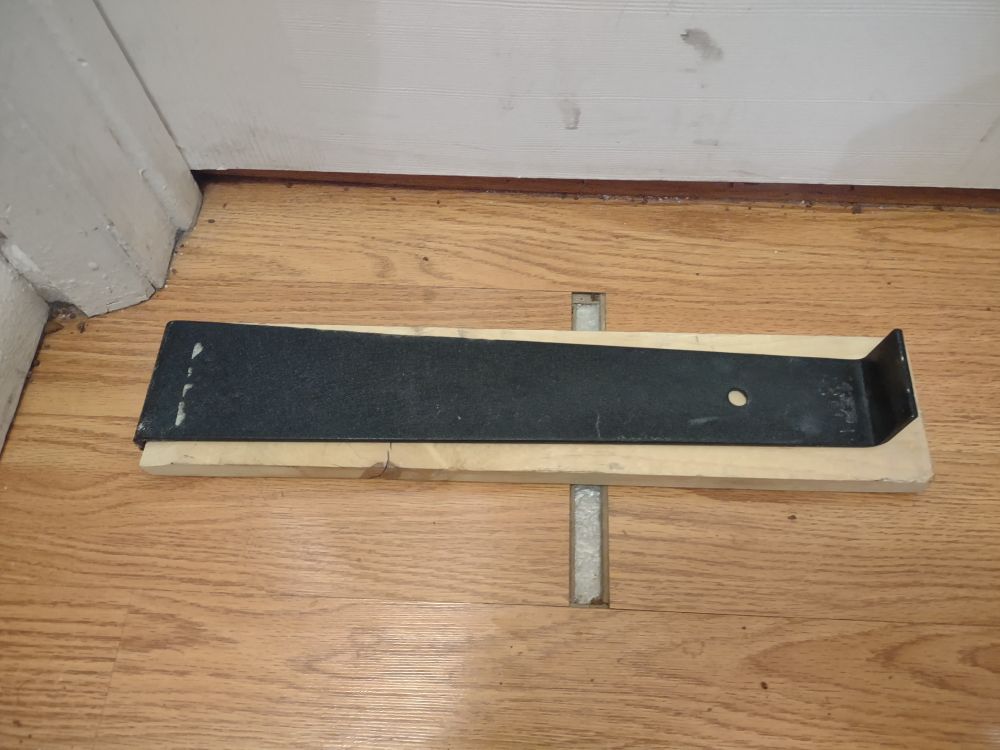 A board has been placed on the tape, with a flooring tool to allow for room to hit the top of the board