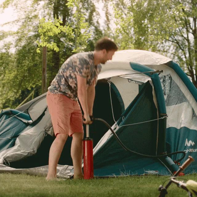 a man pumps up a tent with a red pump that says ' m ' on it