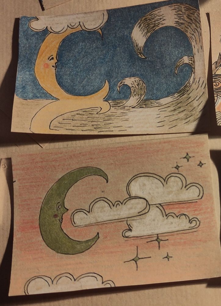 Zwei ATCs, Querformat, Kraftpapier. Fineliner, Buntstifte, Metallicmarker. Oben: Mond Sichel mit Gesicht links im Bild über dem Meer mit Spiegelung, darüber eine Wolke, rechts große Wellen. Metallicblauer Hintergrund. Unten: Wolken und stilisierte Sterne vor orangerosa Himmel. Links im Bild ist eine große goldene Mondsichel mit Gesicht. 