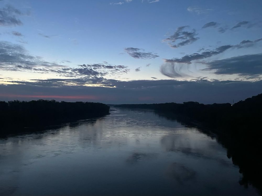 Sunrise over the Missouri River, with a splash of pink lining a band of gray clouds