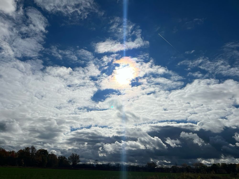 Blue skies with wisps of clouds and a bright sun 