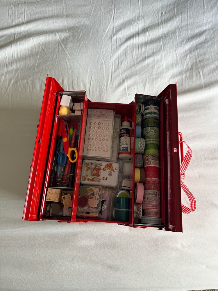 a bright red toolbox opened to show an array of crafting supplies 