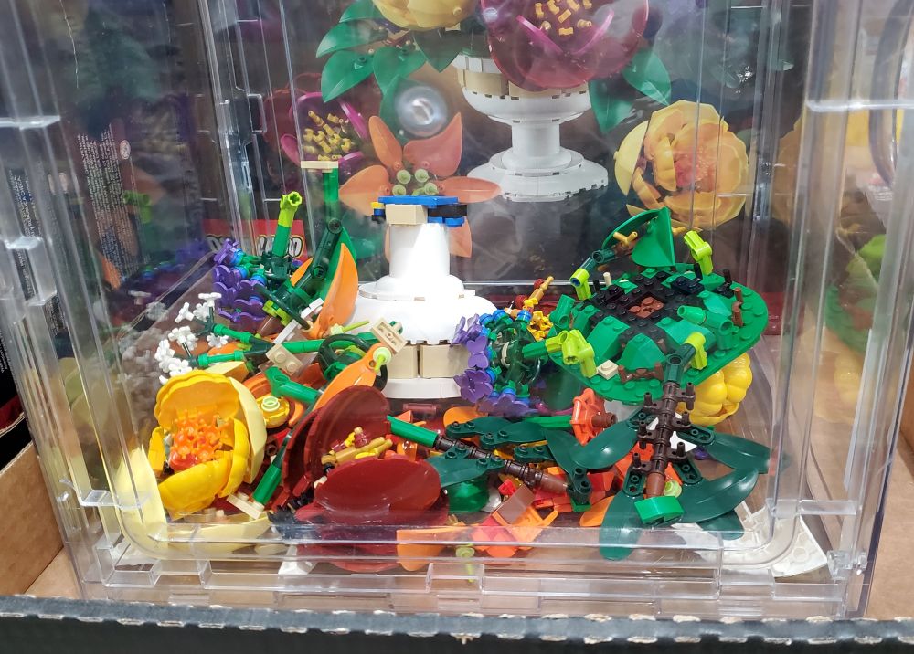 inside a plastic bin where a floral lego bouquet was assembled, but currently in a mess because it looks like someone shook the bin a bit aggressively.
