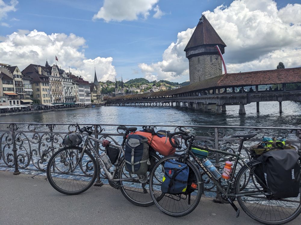 Two bikes leaning along a railing in Lucene, Switzerland. The chapel bridge and downtown areas can be seen in the background. 