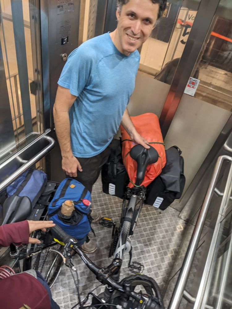 Two bikes and two people squeezed onto a small elevator. 