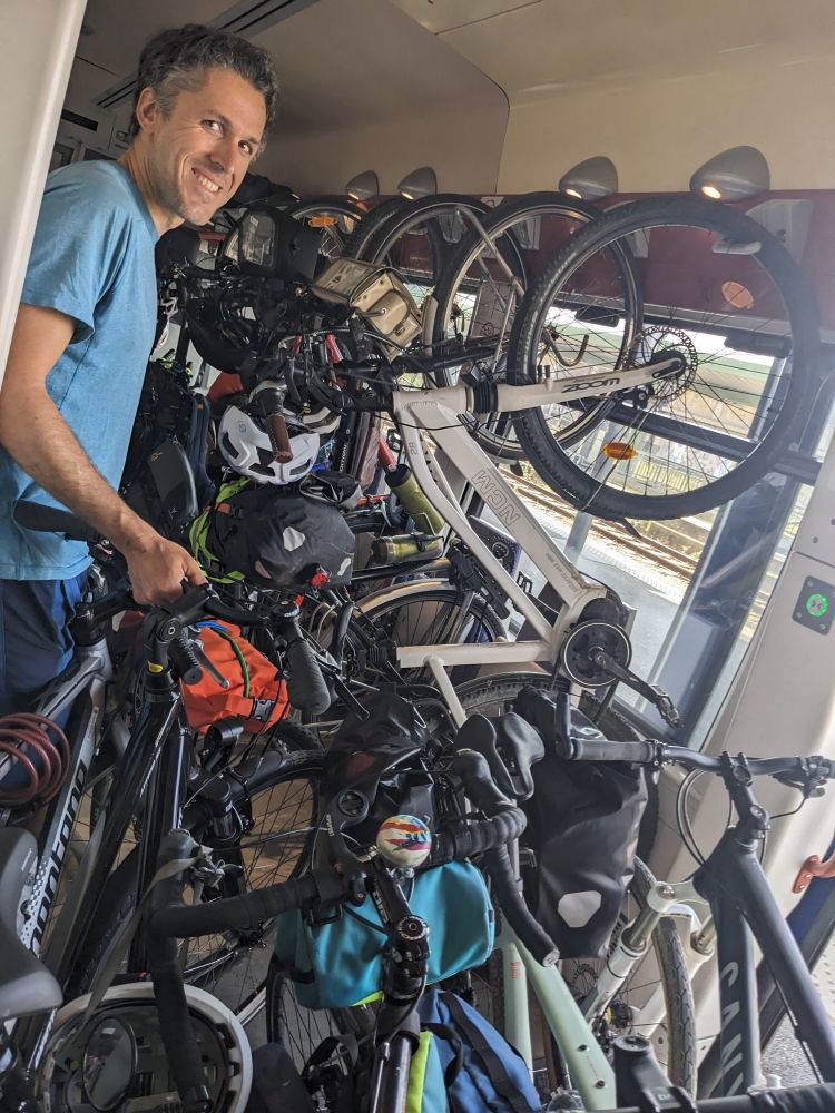 A smiling man in a sea of bikes on a train. 