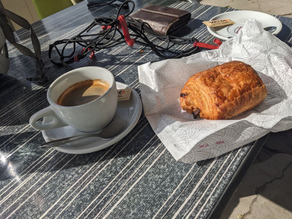 A coffee and a pain au chocolat sitting on a table. 