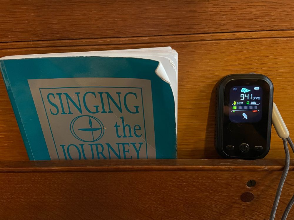 Image of a church pew with a song book and a CO2 meter reading 941ppm 