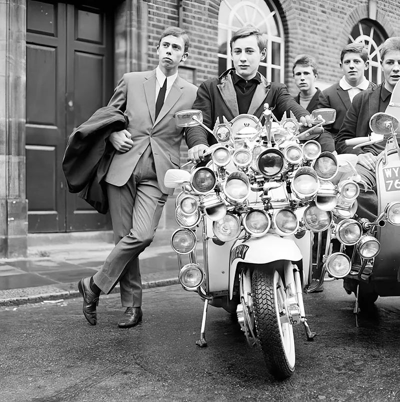 A group of mods, dressed in suits and parkas, show off the modified scooters. Peckham, England, 1964. (Photo by Daily Mirror).
