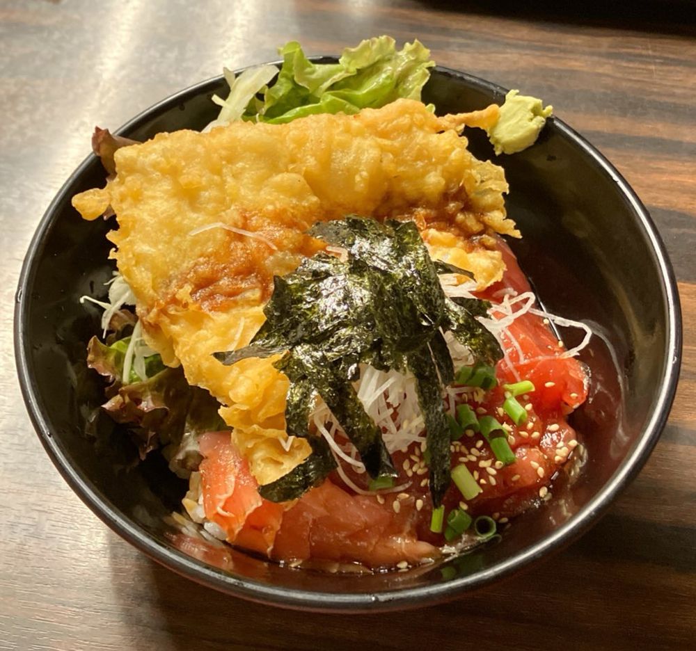 手前に漬けマグロ、奥にマグロのトロ部分の天ぷらのマグロ丼。上にはやや細切りの海苔とツマが乗っています。