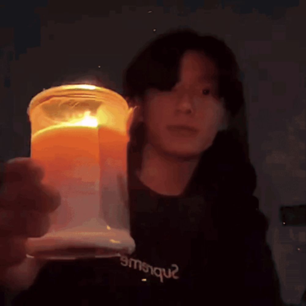 a person wearing a black shirt that says emsique holds a candle