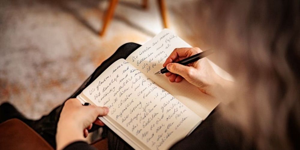 Schreibende Hand und Text in einem Notizbuch.