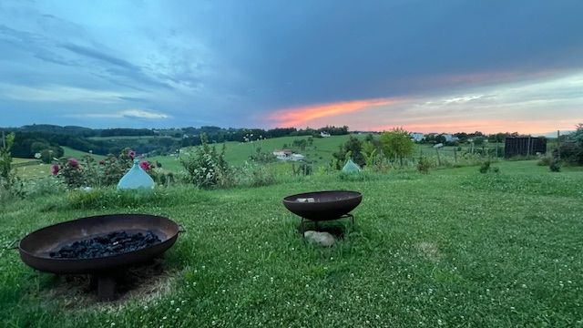 Sonnenuntergang beim Schreibretreat im Burgenland, zeigt Wiese mit Feuerschalen und rotem Himmel.