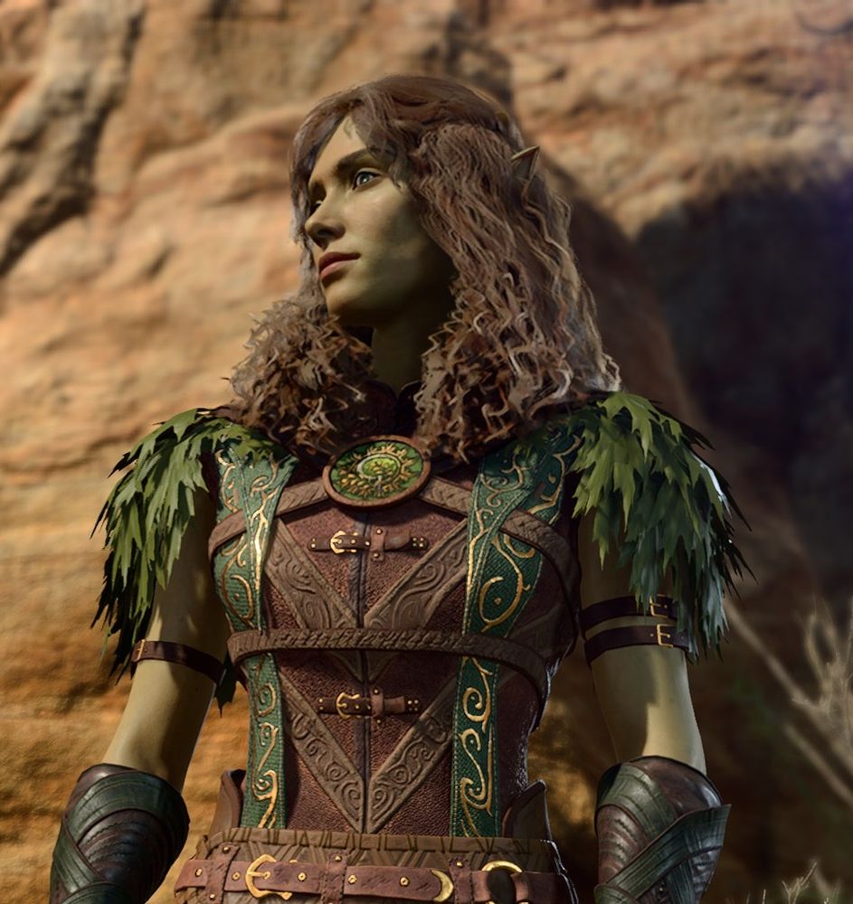 This screenshot is of Meliahwyl. The angle is about midwaist looking up at her. The image is cropped and begins around her waist. She is wearing typical green and brown druidic leather armor with leaf adornments at the shoulders. She is looking ahead of her with her head slightly turned to her right, with an interested, if not very slightly alarmed, expression. Her hair is long, brown, and curly. Her skin is a pale-pistachio greenish tan.