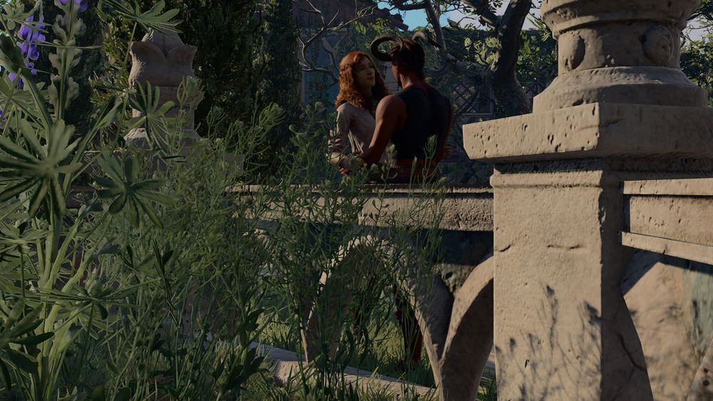 In this screenshot, foliage and a stone fence are in the foreground. Beyond it in the background, though very much in focus, are Wyll and Meliahwyl. They are semi-embraced, holding each other's hands. Meliawyl is facing the viewer and, despite the distance, a smile can be seen on her face. Wyll's back is facing the viewer and his expression cannot be seen. They are both wearing their standard camp clothes: Meliahwyl, the beige linen tunic with green and brown accents, and Wyll, his cropped, raggedy dark-grey and red "earthly garb". 