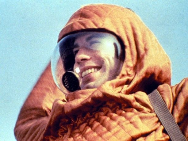 John Travolta in 'The boy in the Plastic Bubble', released in 1976. He is smiling, but wearing a padded orange space suit sort of thing, because his character is immunologically compromised. 