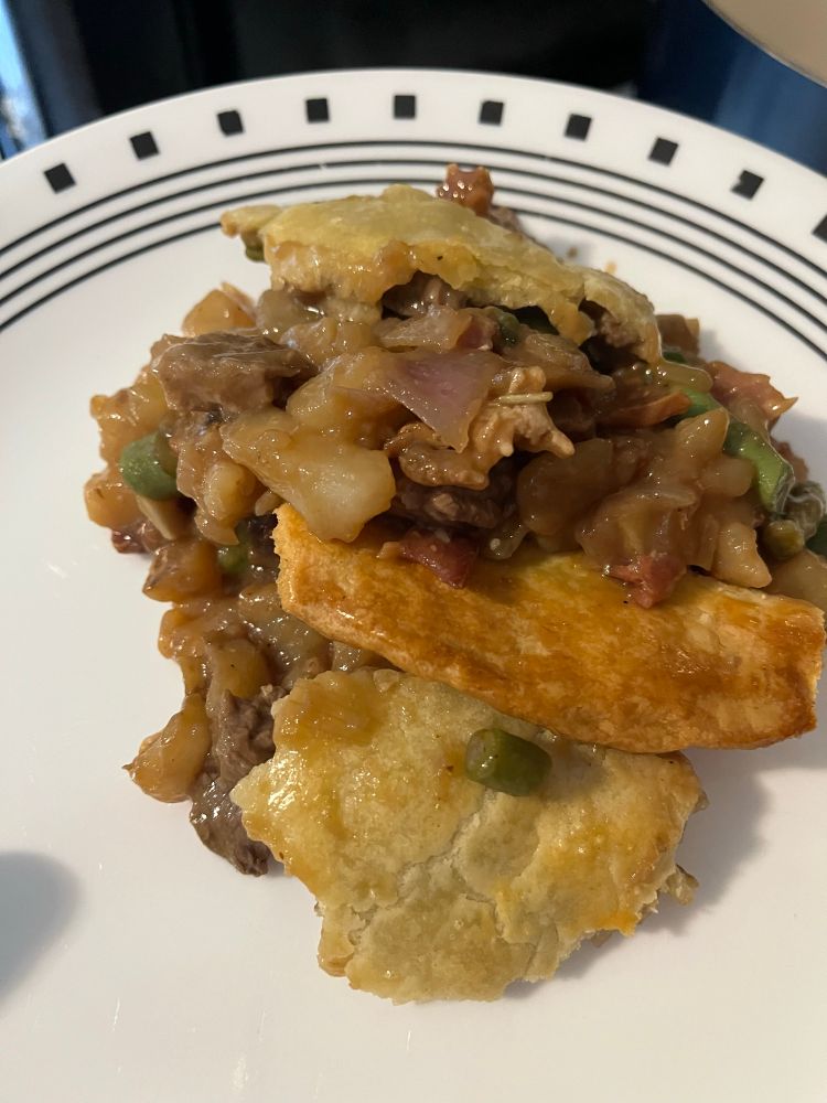 Steak and Potato Pie on white plate with black trim.