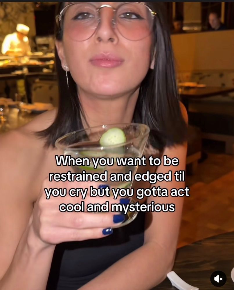 image of a brunette woman holding an alcoholic drink with a meme caption “When you want to be restrained and edged til you cry but you gotta act cool and mysterious”