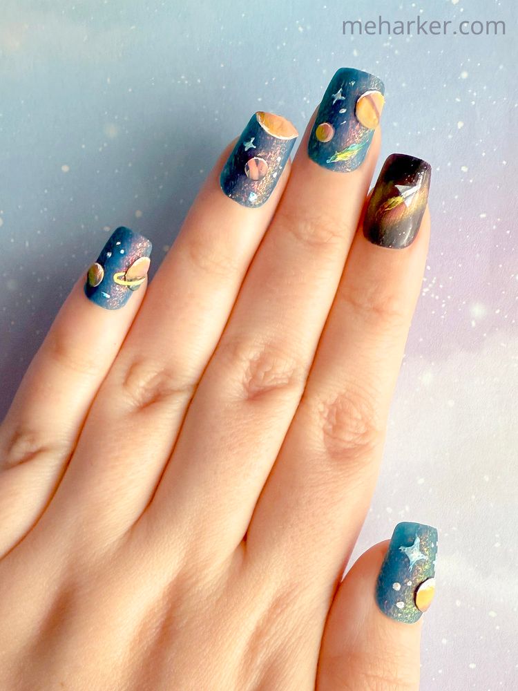 A hand show-casing a space-themed manicure on all nails.