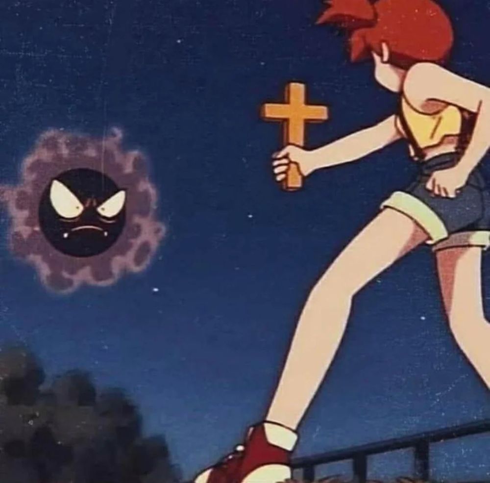 A girl with red hair, yellow crop top, and jean shorts points a cross at Ghastly. A round black ball with purple gas surrounding it.