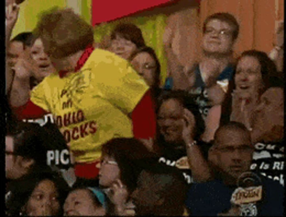 a man in a yellow shirt that says pablo rocks stands in front of a crowd