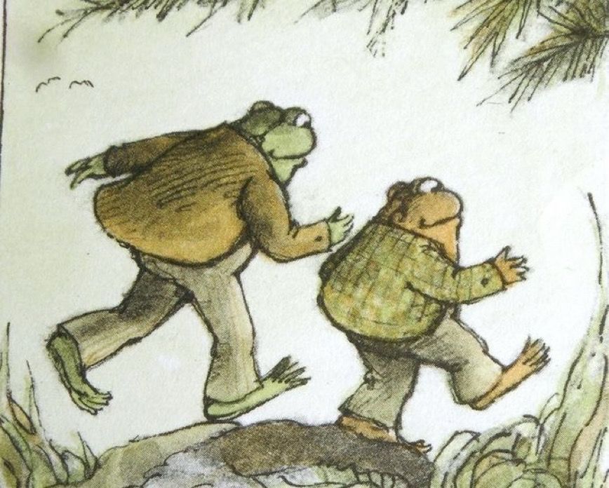 Drawing of Frog and Toad by Arnold Lobel walking side by side away from the viewer. Frog is in a brown jacket and tan vertical striped slacks. Toad is in a green plaid jacket and pale green slacks. 