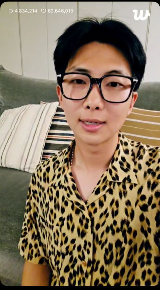 Kim Namjoon aka RM of BTS from Weverse live from the day of his discharge from the military June 10th 2025. He is wearing a leopard print button up shirt and black framed glasses. His hair is black and his forehead is visible. 
