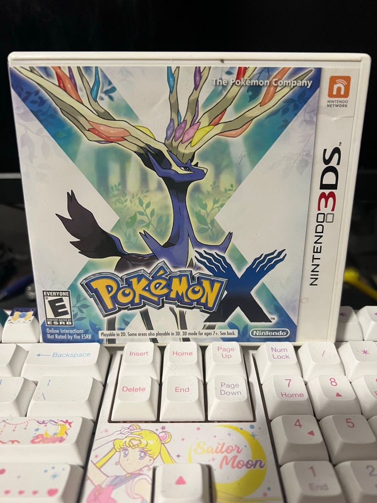 A picture of Pokemon X on the 3DS on top of a Sailor Moon keyboard.