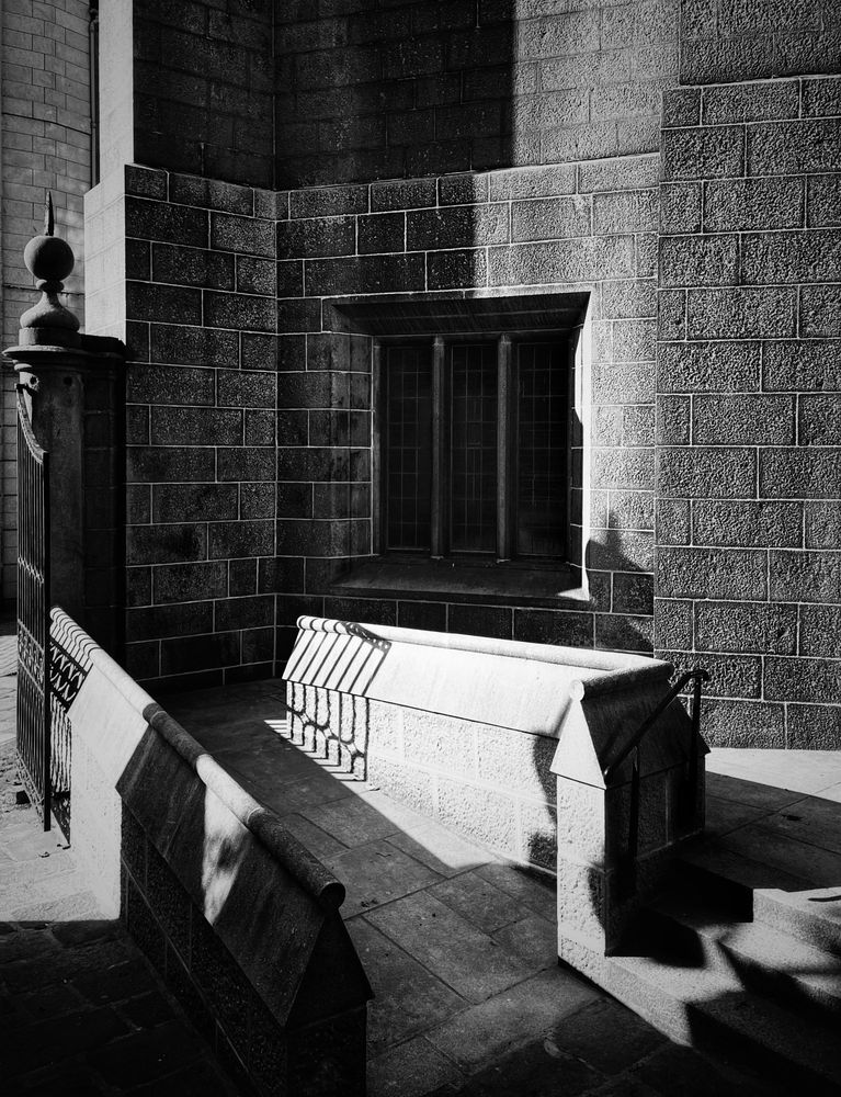 A monochrome image of a part of a church and gate somewhere in Scotland, on “another lovely sunny day” which are never really good for anything apart from monochrome images.
