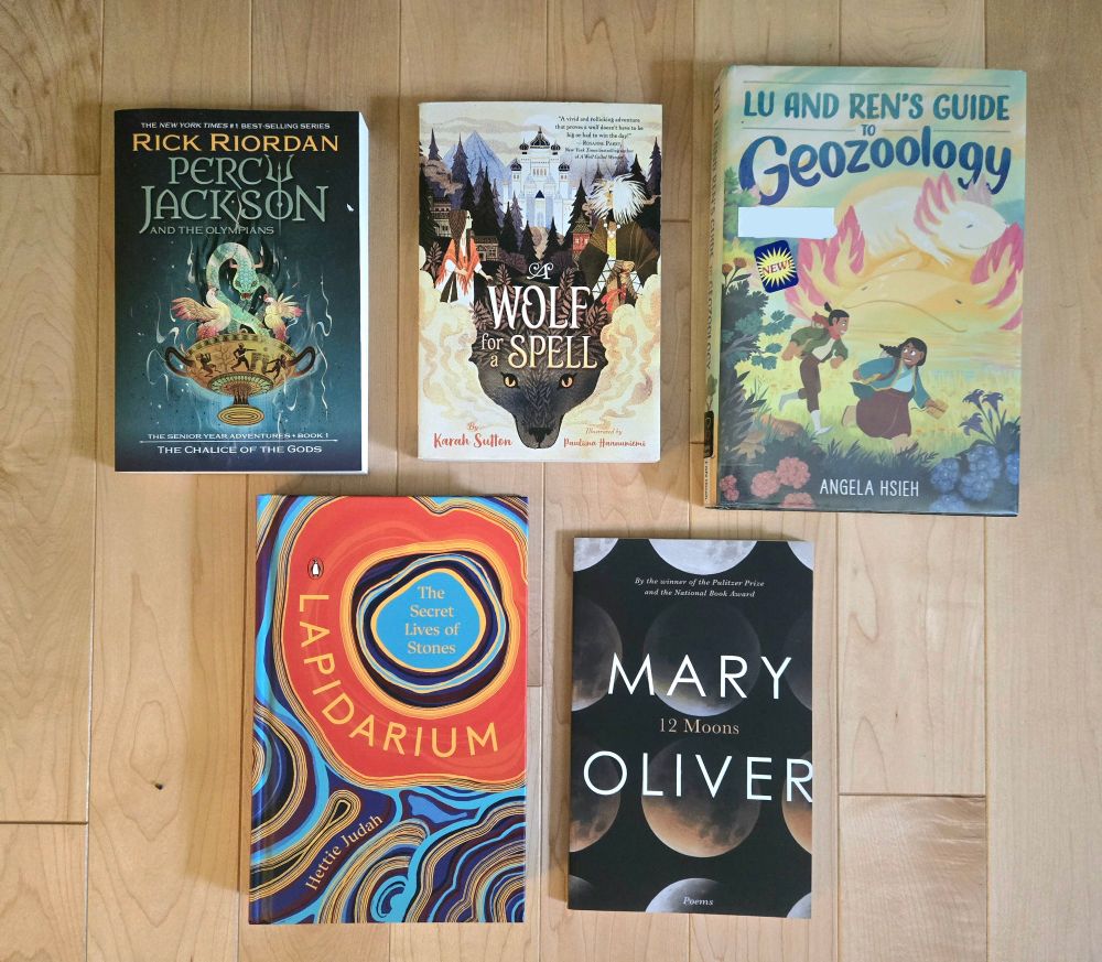 Five books: "The Chalice of the Gods" by Rick Riordan, "A Wolf for a Spell" by Karah Sutton,  "Lu and Ren's Guide to Geozoology" by Angela Hseih, "Lapidarium" by Hettie Judah, and "Twelve Moons" by Mary Oliver.