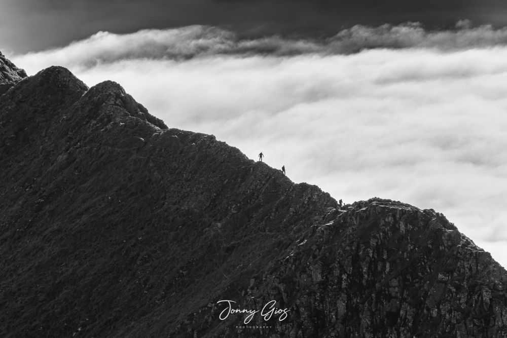 3 walkers going along striding edge with the inversion behind them 