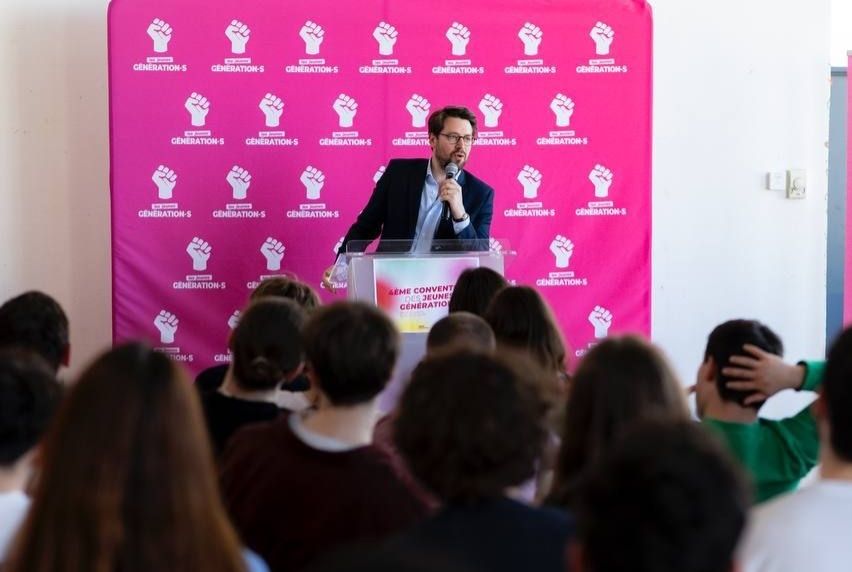 Photo de Benjamin Lucas parlant devant des militants et militantes assis et assises.